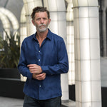 Man wearing a navy blue hemp shirt standing in an indoor setting with architectural elements.