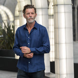 Man wearing a navy blue hemp shirt standing in an indoor setting with architectural elements.