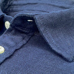 Close-up of a navy blue hemp shirt collar with buttons.