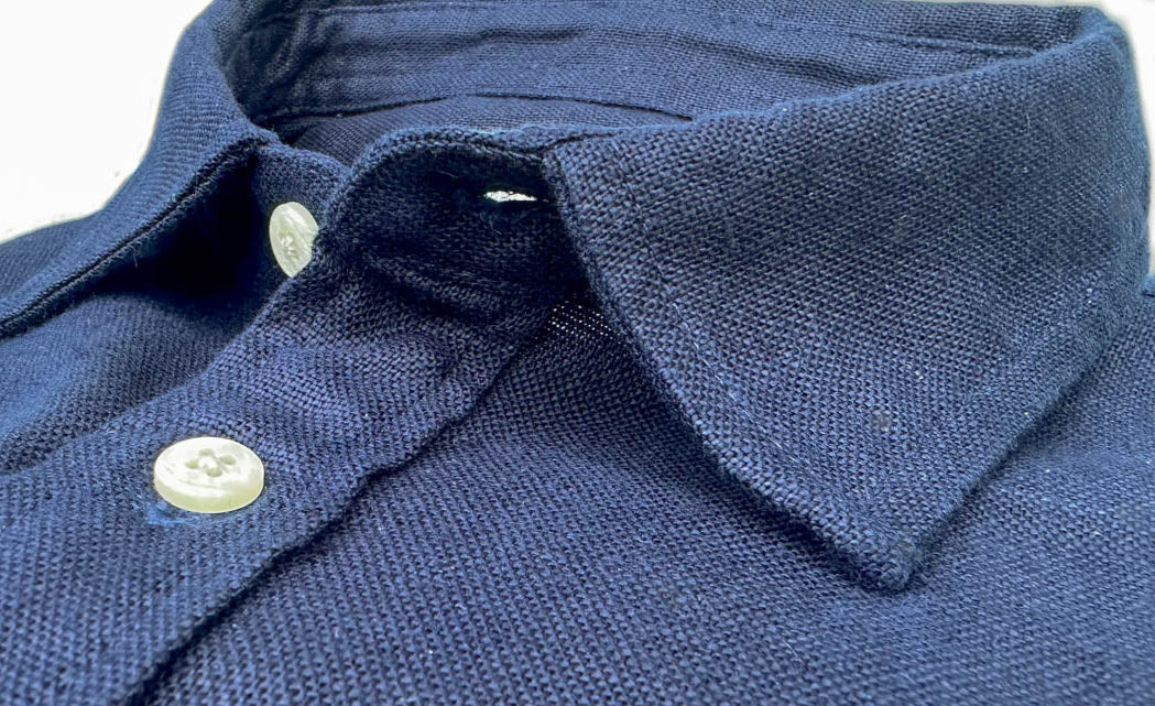 Close-up of a navy blue hemp shirt collar with buttons.