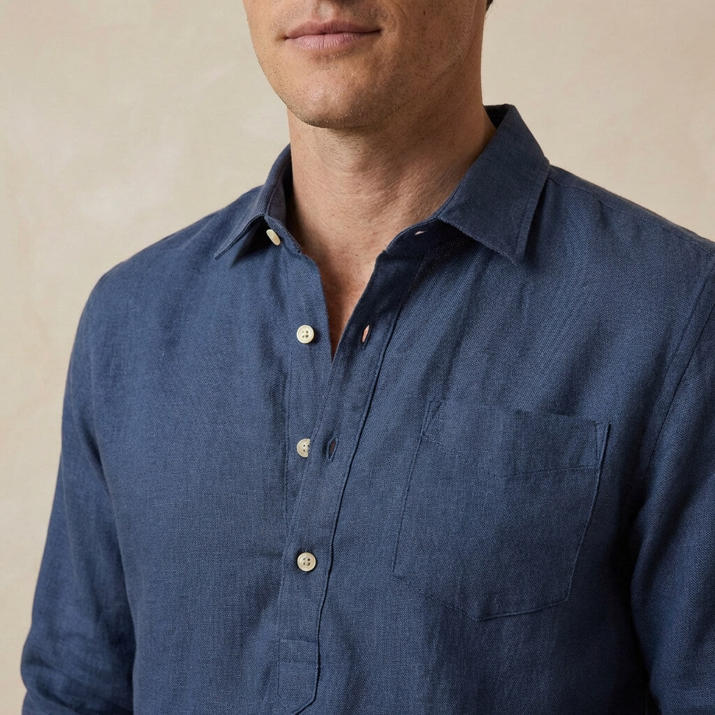navy blue button-up hemp shirt worn by a person on a beige background with focus on the chest pocket and quarter length placket