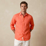 Man wearing a coral hemp shirt and white pants against a beige background