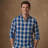 model wears a blue and white thick check winter heavy hemp shirt with sleeves rolled up with a warm sand coloured background.