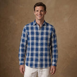 a model wears a blue and white thick check winter heavy hemp shirt with sleeves rolled down with a warm sand coloured background.