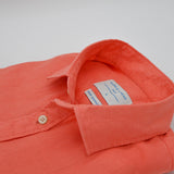 Coral-colored shirt with a button and collar on a light gray background