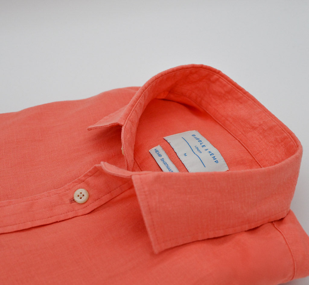 Coral-colored shirt with a button and collar on a light gray background