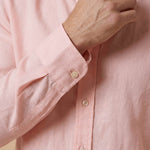 closeup shot of the cuff and button being fastened on a hemp shirt colour peach