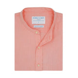 Folded pink hemp shirt with grandad collar and with a label on a white background
