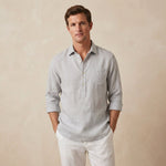 Man wearing a light grey long-sleeve shirt made from hemp fabric and white trousers against a beige background