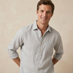Man wearing a light grey shirt against a beige background