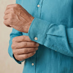 closeup shot of the cuff and button being fastened on a hemp shirt colour kingfisher blue