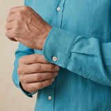 closeup shot of the cuff and button being fastened on a hemp shirt colour kingfisher blue