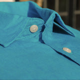 Close-up of a blue shirt collar with buttons against a blurred background