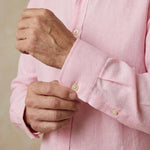 closeup shot of the cuff and button being fastened on a hemp shirt colour pink