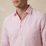 Light pink button-up hemp shirt worn by a person on a beige background with focus on the chest pocket and quarter length placket