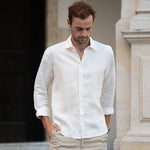 Man wearing a white shirt made from sustainable hemp fabric and beige pants walking outdoors.