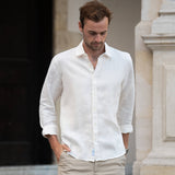 Man wearing a white shirt made from sustainable hemp fabric and beige pants walking outdoors.