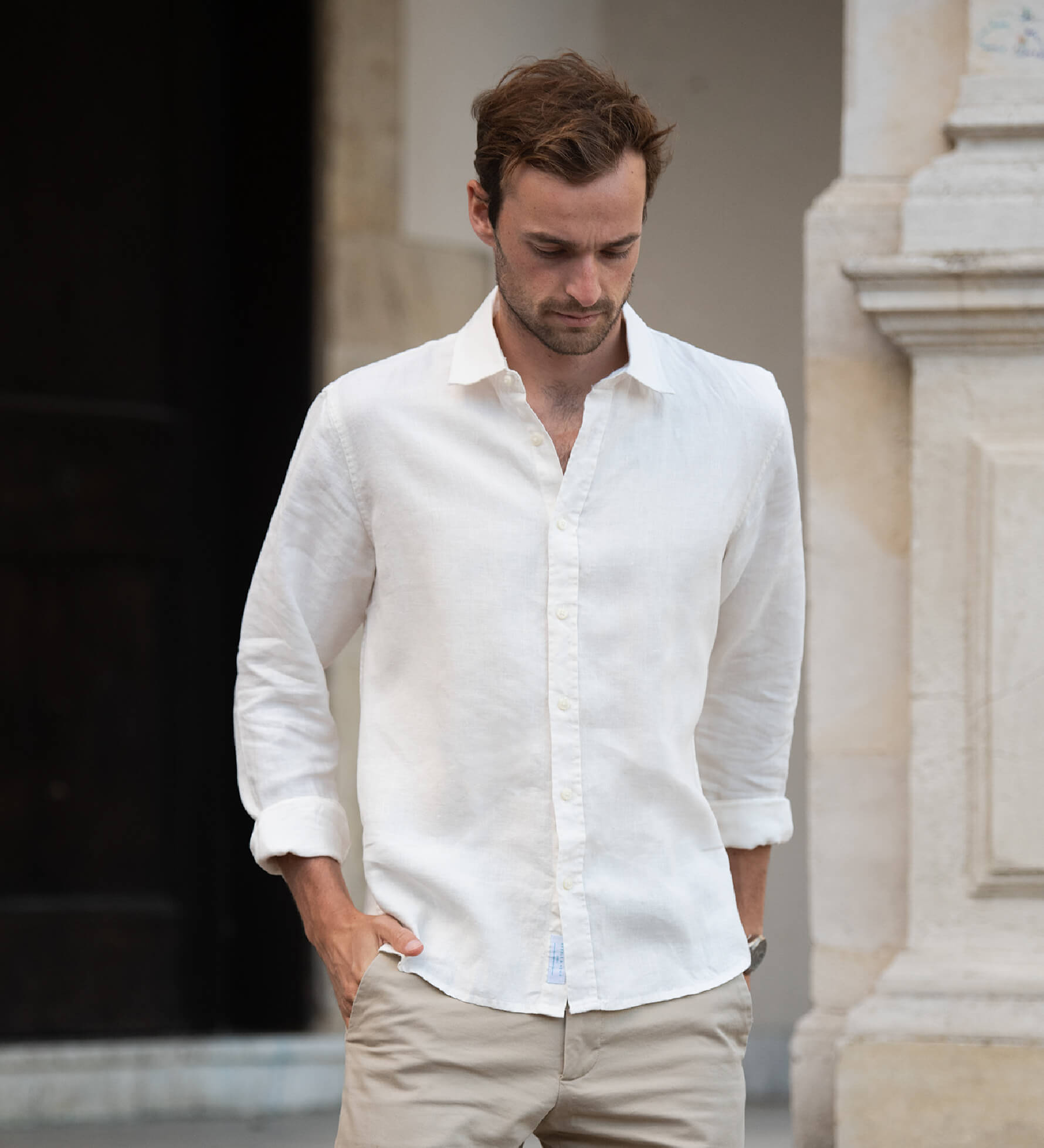 Man wearing a white shirt made from sustainable hemp fabric and beige pants walking outdoors.