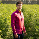 Man standing in a field of green plants wearing a purple shirt.
