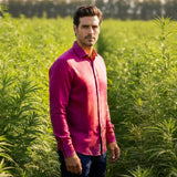 Man standing in a field of green plants wearing a purple shirt.