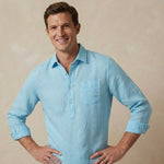 close up shot of a man wearing a light blue hemp fabric shirt against a beige background