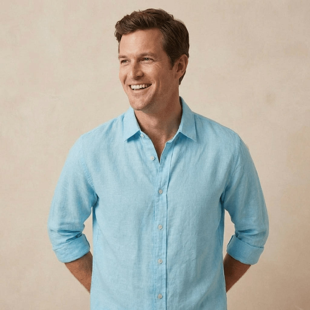 a 35 year old man models a light blue hemp shirt which is a better fabric than linen in front of a beige coloured backdrop