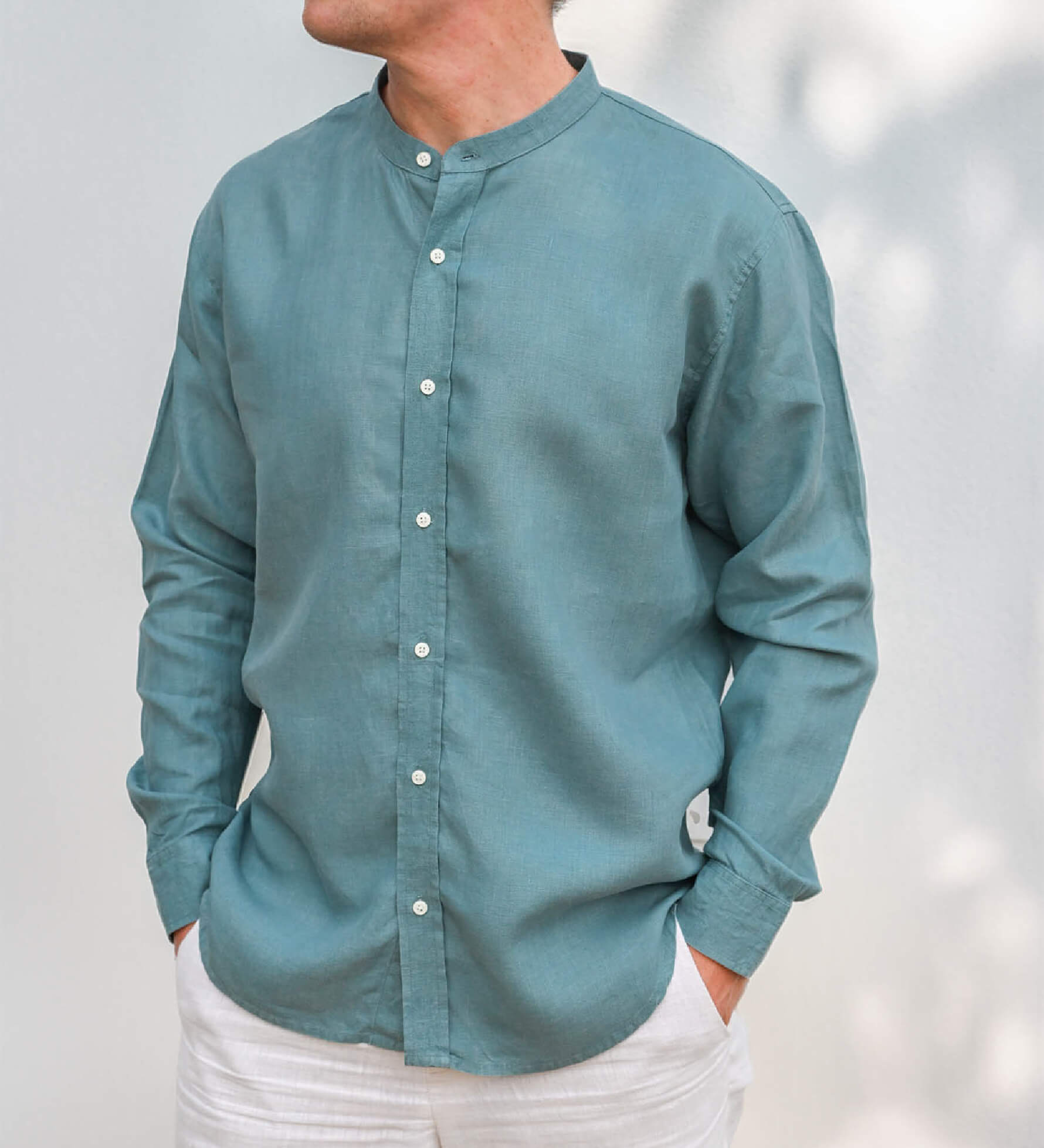 Teal long-sleeve, collarless hemp shirt worn by a person against a light background