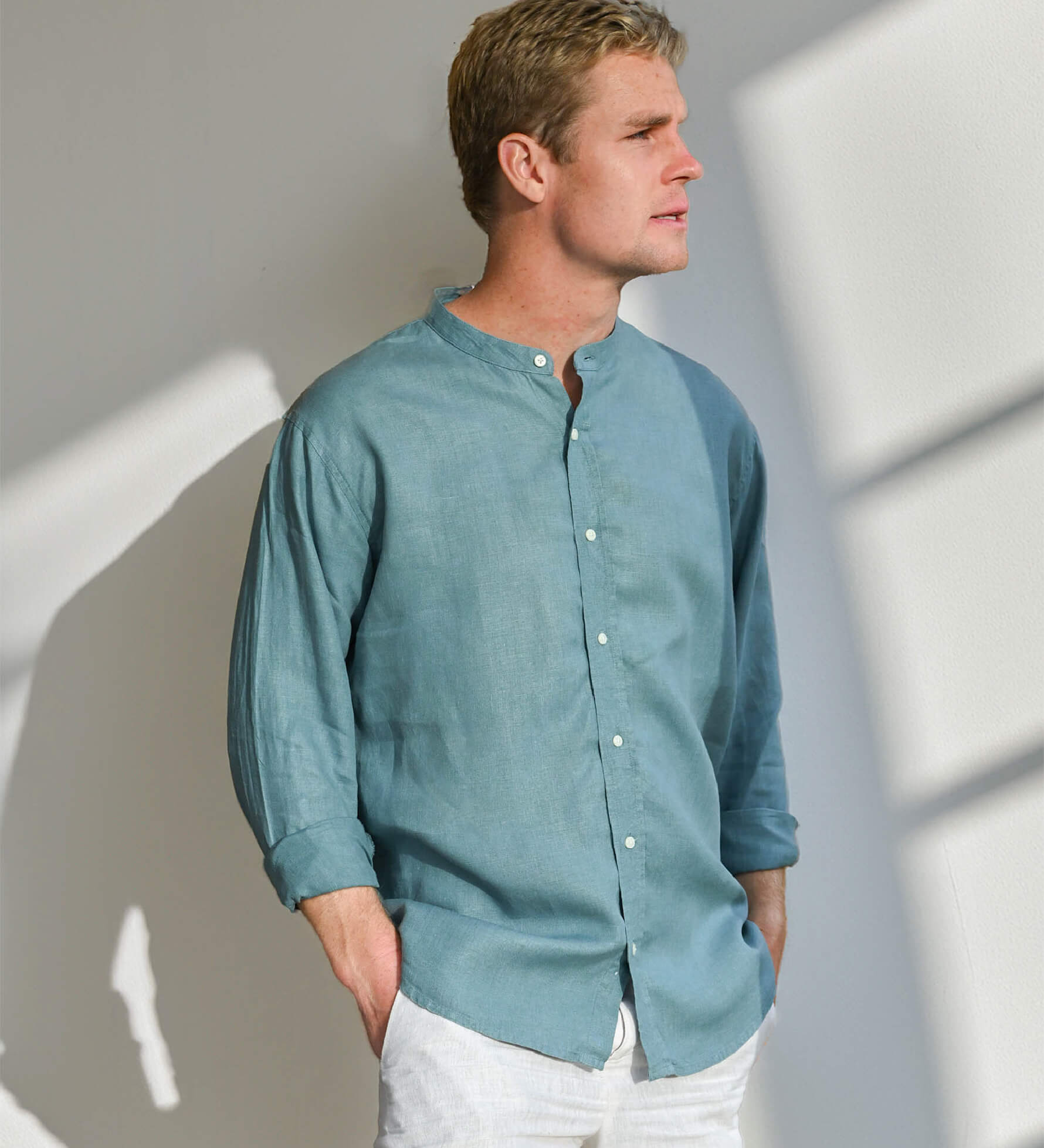 Man wearing a teal button-up, collarless shirt of hemp fabric against a light background
