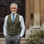 man in formal waistcoat made from hemp fabric in green colour standing in front of smart door and flowerbed