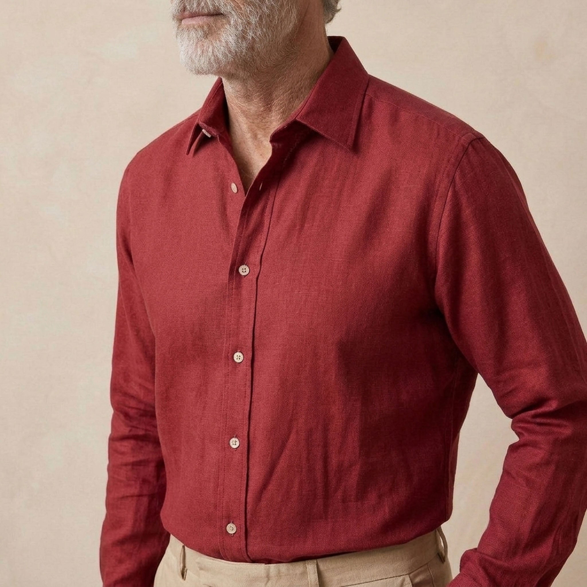 A man wearing a long-sleeve button-down hemp shirt in a deep red or burgundy shade, paired with beige trousers, against a neutral beige background.