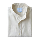 Folded white hemp grandad collar shirt with a visible label on a white background