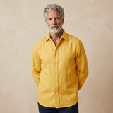 man wears yellow hemp shirt in heavy weight of fabric in front of beige backdrop