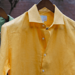 a closeup shot of a yellow hemp shirt on a hanger 