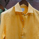 a closeup shot of a yellow hemp shirt on a hanger 