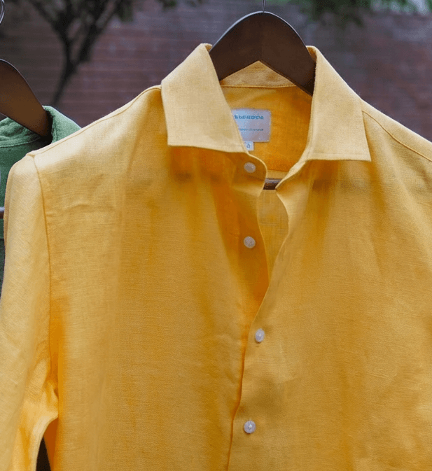 a closeup shot of a yellow hemp shirt on a hanger 