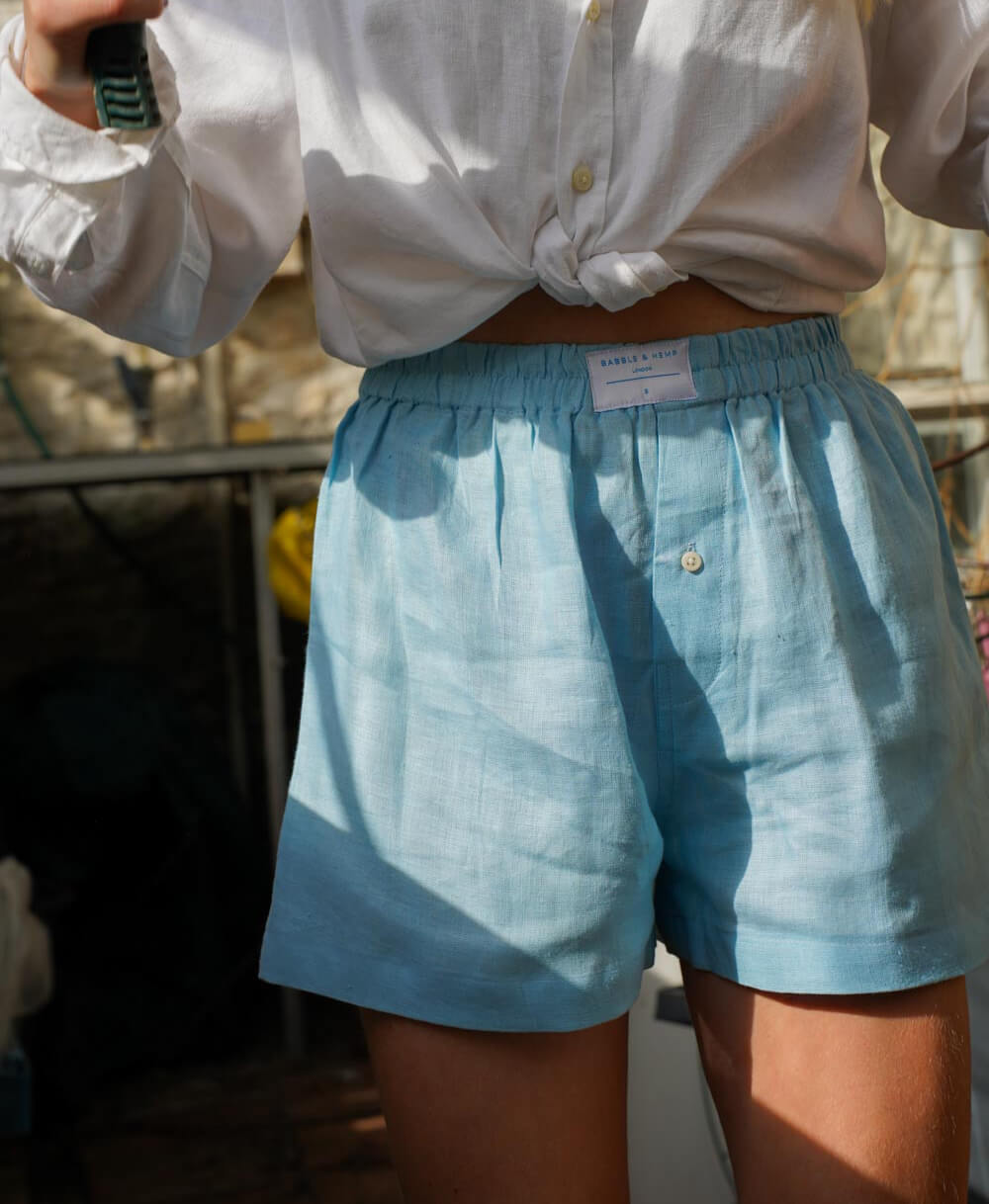 Person wearing light blue hemp boxer shorts and a white shirt with a blurred background