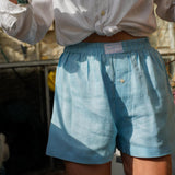 Person wearing light blue hemp boxer shorts and a white shirt with a blurred background