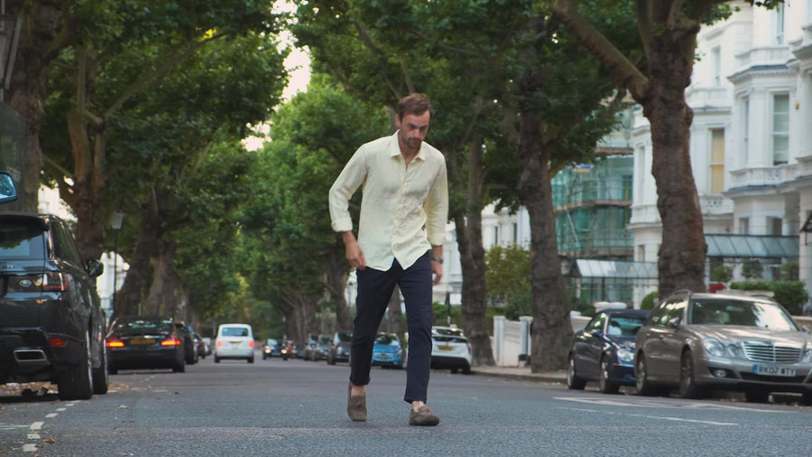 a video of a man walking along a road whilst wearing a yellow hemp shirt
