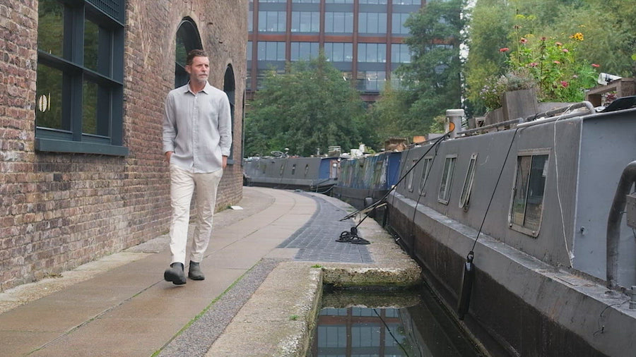 model walks alongside a river whilst wearing a grey hemp shirt