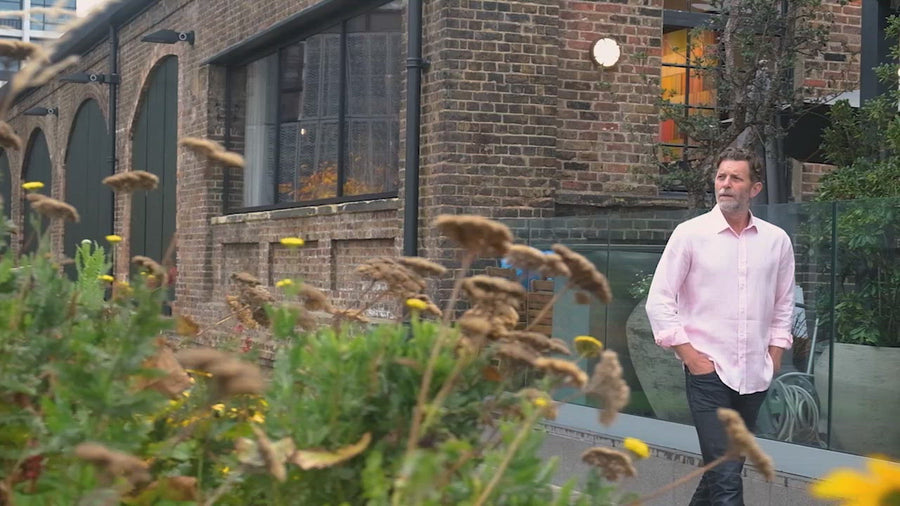a video of a man modelling a pink hemp shirt walking near a canal