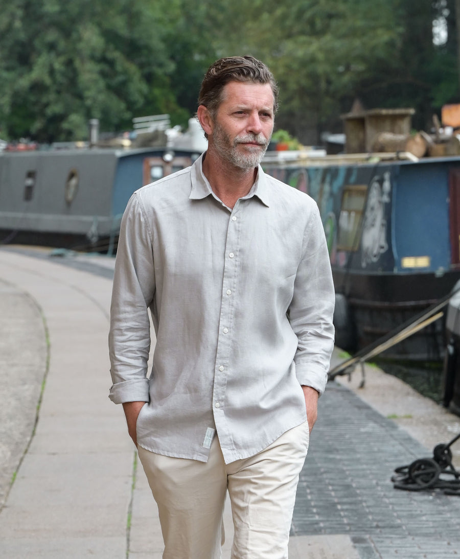 a photo of a model wearing a grey hemp shirt walking near a canal