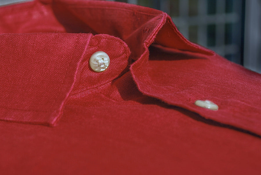 a close up detail image of the buttons on a red hemp shirt